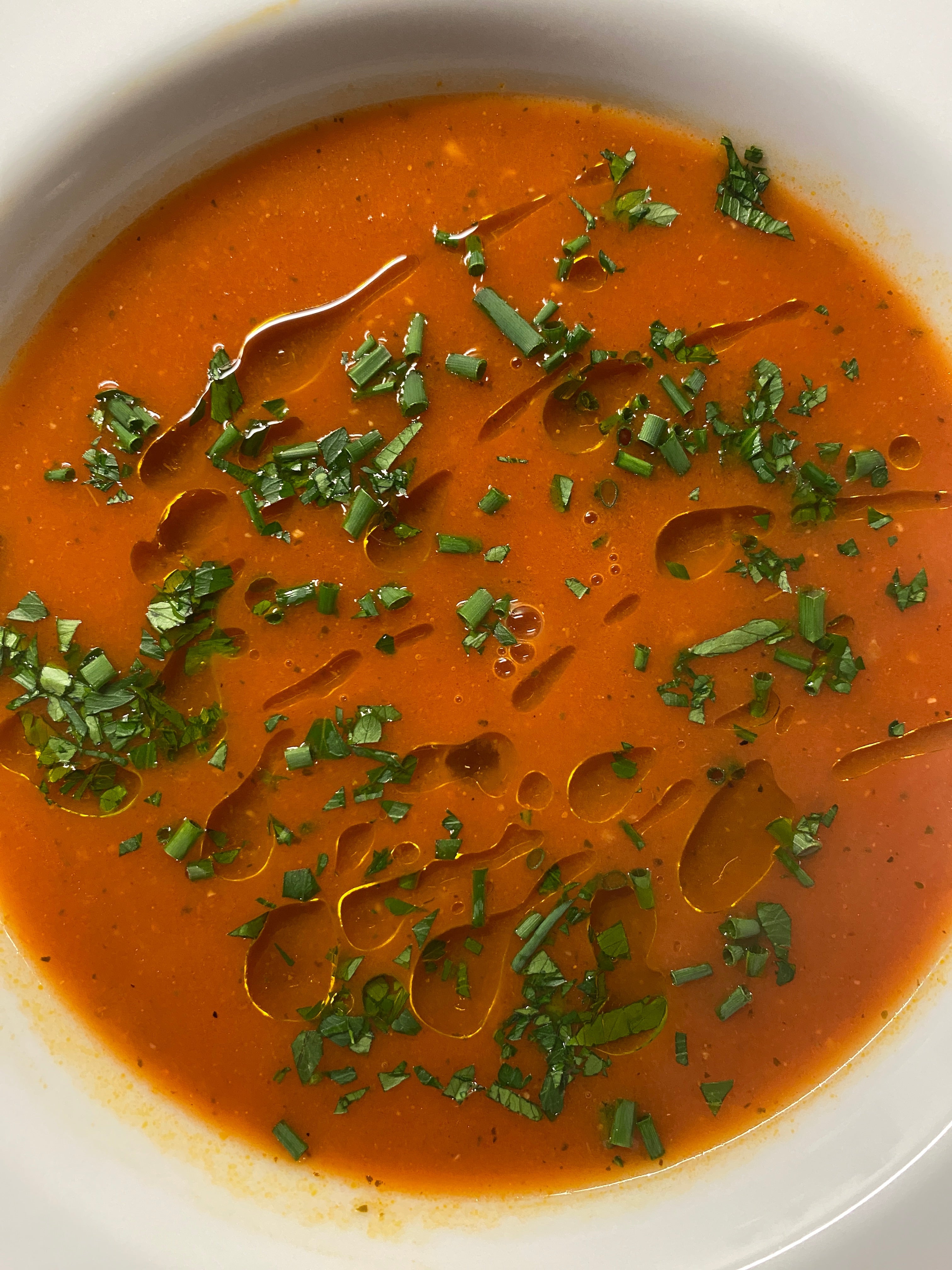 fresh tomato soup drizzled with basil olive oil and dusted with herbs